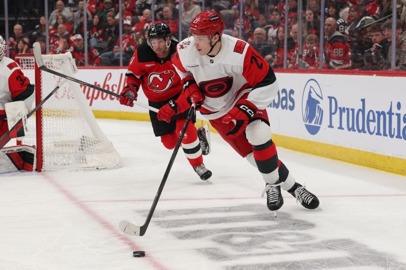 Jan 4, 2026; Newark, New Jersey, USA; Carolina Hurricanes defenseman Alexander Nikishin (21) skates with the puck as New Jersey Devils right wing Stefan Noesen (11) defends during the second period at Prudential Center. Mandatory Credit: Ed Mulholland-Imagn Images