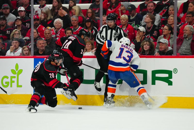 Apr 20, 2024; Raleigh, North Carolina, USA; New York Islanders center Mathew Barzal (13) battles for the puck against Carolina Hurricanes center Seth Jarvis (24) and  center Sebastian Aho (20) during the first period in game one of the first round of the 2024 Stanley Cup Playoffs at PNC Arena. Mandatory Credit: James Guillory-USA TODAY Sports