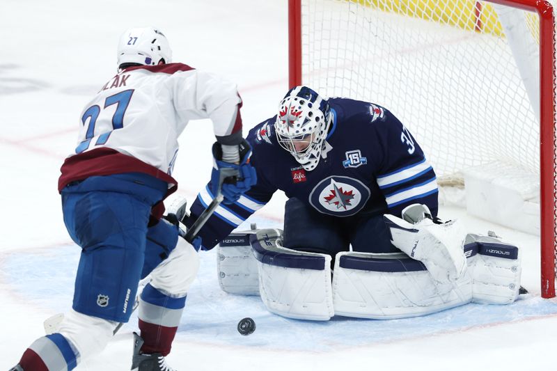 Mar 26, 2026; Winnipeg, Manitoba, CAN; Colorado Avalanche defenseman Brett Kulak (27) shoots on Winnipeg Jets goaltender Connor Hellebuyck (37) in the third period at Canada Life Centre. Mandatory Credit: James Carey Lauder-Imagn Images