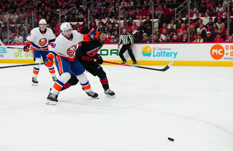 Apr 22, 2024; Raleigh, North Carolina, USA; Carolina Hurricanes center Seth Jarvis (24) and New York Islanders defenseman Alexander Romanov (28) battle over the puck during the first period in game two of the first round of the 2024 Stanley Cup Playoffs at PNC Arena. Mandatory Credit: James Guillory-USA TODAY Sports