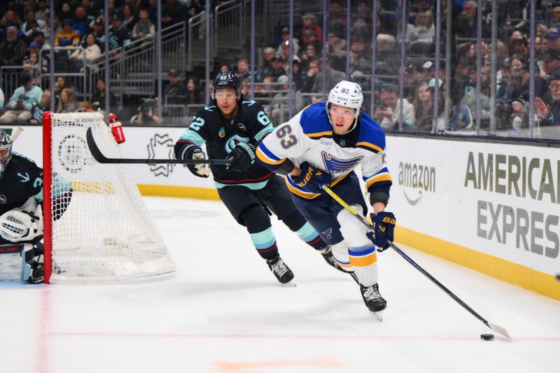 Apr 12, 2025; Seattle, Washington, USA; St. Louis Blues left wing Jake Neighbours (63) plays the puck while defended by Seattle Kraken defenseman Brandon Montour (62) during the third period at Climate Pledge Arena. Mandatory Credit: Steven Bisig-Imagn Images