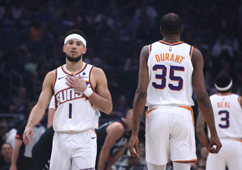 LOS ANGELES, CALIFORNIA - APRIL 10: Devin Booker #1 of the Phoenix Suns reacts as he walks past Kevin Durant #35 during the first half against the LA Clippers at Crypto.com Arena on April 10, 2024 in Los Angeles, California. User is consenting to the terms and conditions of the Getty Images License Agreement.  (Photo by Harry How/Getty Images)