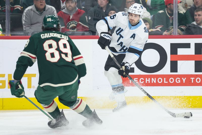 Jan 23, 2025; Saint Paul, Minnesota, USA; Utah Hockey Club center Alexander Kerfoot (15) shoots the puck as Minnesota Wild center Frederick Gaudreau (89) defends during the first period at Xcel Energy Center. Mandatory Credit: Matt Krohn-Imagn Images