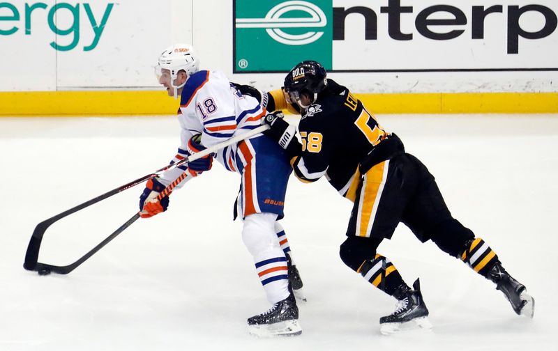 Feb 23, 2023; Pittsburgh, Pennsylvania, USA;  Edmonton Oilers left wing Zach Hyman (18) moves the puck against Pittsburgh Penguins defenseman Kris Letang (58) during the second period at PPG Paints Arena. Edmonton won 7-2. Mandatory Credit: Charles LeClaire-USA TODAY Sports