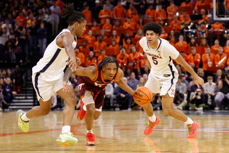 Feb 1, 2025; Charlottesville, Virginia, USA; Virginia Tech Hokies forward Tobi Lawal (1) dribbles the ball between Virginia Cavaliers guard Dai Dai Ames (7) and Cavaliers forward Jacob Cofie (5) in the first half at John Paul Jones Arena. Mandatory Credit: Amber Searls-Imagn Images