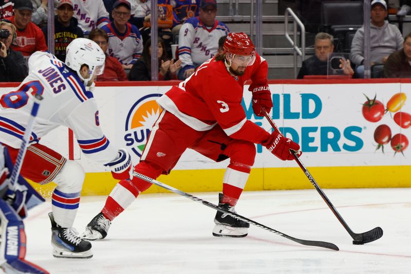 Oct 17, 2024; Detroit, Michigan, USA;  Detroit Red Wings defenseman Justin Holl (3) skates with the puck defended by New York Rangers defenseman Zac Jones (6) in the second period at Little Caesars Arena. Mandatory Credit: Rick Osentoski-Imagn Images