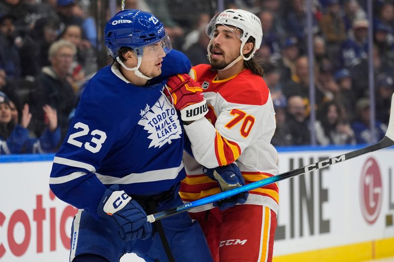 Oct 28, 2025; Toronto, Ontario, CAN; Calgary Flames forward Ryan Lomberg (70) battles with Toronto Maple Leafs forward Matthew Knies (23) during the third period at Scotiabank Arena. Mandatory Credit: John E. Sokolowski-Imagn Images