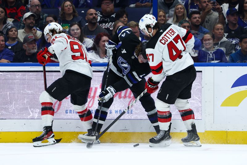 Nov 16, 2024; Tampa, Florida, USA; Tampa Bay Lightning center Conor Geekie (14) New Jersey Devils center Paul Cotter (47) and center Dawson Mercer (91) battle for the puck in the first period at Amalie Arena. Mandatory Credit: Nathan Ray Seebeck-Imagn Images