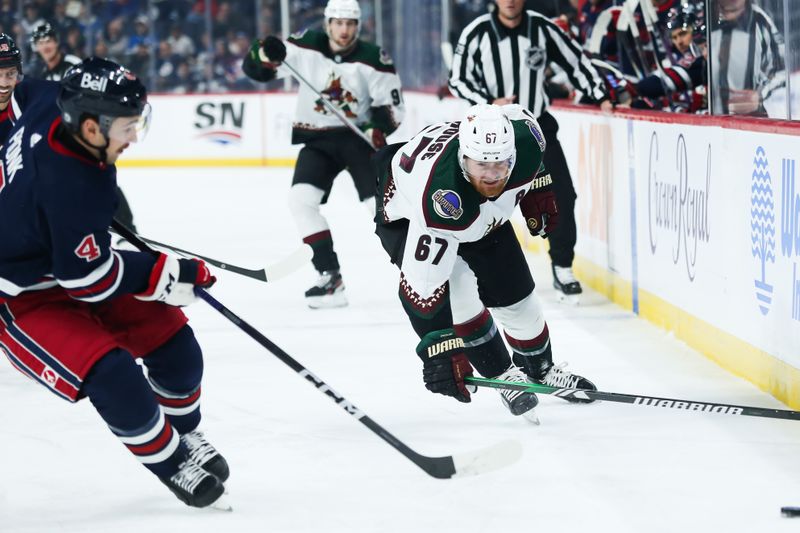 Nov 18, 2023; Winnipeg, Manitoba, CAN; Arizona Coyotes forward Lawson Crouse (67) and Winnipeg Jets defenseman Neal Pionk (4) chase after the puck during the first period at Canada Life Centre. Mandatory Credit: Terrence Lee-USA TODAY Sports