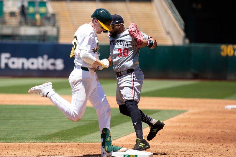 Jun 22, 2024; Oakland, California, USA; Minnesota Twins first baseman Carlos Santana (30) tags the bag ahead of Oakland Athletics third baseman Tyler Nevin (26) during the second inning at Oakland-Alameda County Coliseum. Mandatory Credit: D. Ross Cameron-USA TODAY Sports