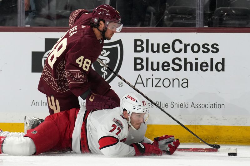 Mar 3, 2023; Tempe, Arizona, USA; Carolina Hurricanes defenseman Brett Pesce (22) and Arizona Coyotes center Jean-Sebastien Dea (48) go after a loose puck during the second period at Mullett Arena. Mandatory Credit: Joe Camporeale-USA TODAY Sports