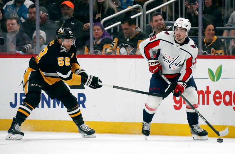 Mar 7, 2024; Pittsburgh, Pennsylvania, USA; Washington Capitals center Hendrix Lapierre (29) moves the puck against Pittsburgh Penguins defenseman Kris Letang (58) during the first period at PPG Paints Arena. Mandatory Credit: Charles LeClaire-USA TODAY Sports