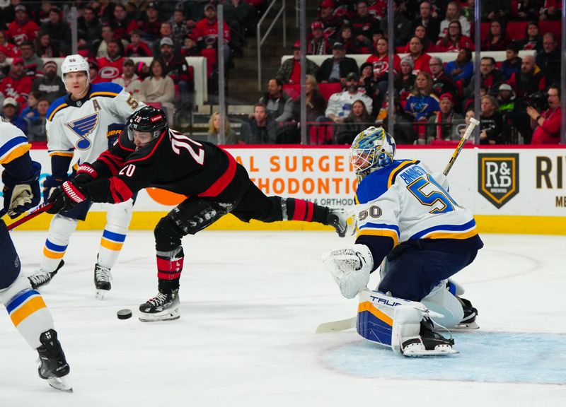 Jan 6, 2024; Raleigh, North Carolina, USA; Carolina Hurricanes center Sebastian Aho (20) tries to tip the puck against St. Louis Blues goaltender Jordan Binnington (50) during the first period at PNC Arena. Mandatory Credit: James Guillory-USA TODAY Sports