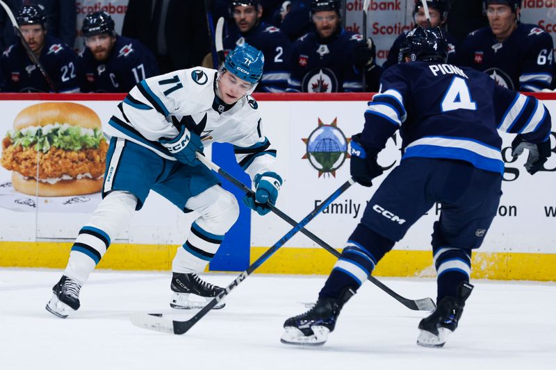 Feb 24, 2025; Winnipeg, Manitoba, CAN;  San Jose Sharks forward Macklin Celebrini (71) receives a pass in front of Winnipeg Jets defenseman Neal Pionk (4) during the first period at Canada Life Centre. Mandatory Credit: Terrence Lee-Imagn Images