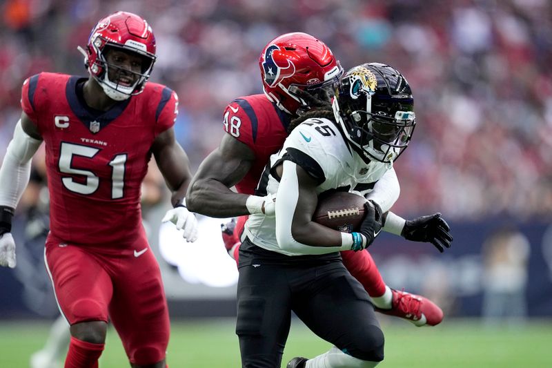 Jacksonville Jaguars running back D'Ernest Johnson (25) gains yards after a catch as Houston Texans' Christian Harris (48) and Will Anderson Jr. (51) make the stop on the play in the first half of an NFL football game in Houston, Sunday, Nov. 26, 2023. (AP Photo/Eric Gay)