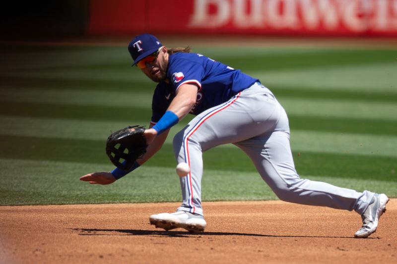 May 8, 2024; Oakland, California, USA; Texas Rangers third baseman Davis Wendzel (38) makes a backhand stop of a ground ball by Oakland Athletics first baseman Tyler Nevin during the first inning at Oakland-Alameda County Coliseum. Mandatory Credit: D. Ross Cameron-USA TODAY Sports