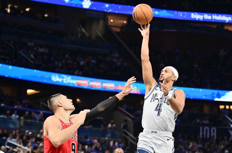 ORLANDO, FLORIDA - NOVEMBER 27: Jalen Suggs #4 of the Orlando Magic shoots a basket against Nikola Vucevic #9 of the Chicago Bulls in the first half of a game at Kia Center on November 27, 2024 in Orlando, Florida. NOTE TO USER: User expressly acknowledges and agrees that, by downloading and or using this photograph, User is consenting to the terms and conditions of the Getty Images License Agreement. (Photo by Julio Aguilar/Getty Images)