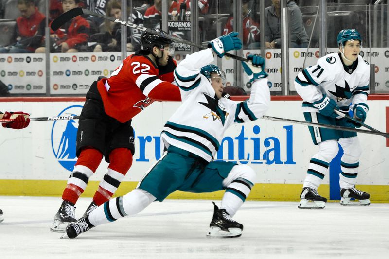 Nov 10, 2024; Newark, New Jersey, USA; New Jersey Devils defenseman Brett Pesce (22) checks San Jose Sharks center Ty Dellandrea (53) during the third period at Prudential Center. Mandatory Credit: John Jones-Imagn Images