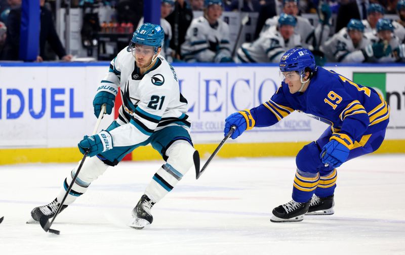 Mar 4, 2025; Buffalo, New York, USA;  San Jose Sharks center Alexander Wennberg (21) skates with the puck as Buffalo Sabres center Peyton Krebs (19) defends during the first period at KeyBank Center. Mandatory Credit: Timothy T. Ludwig-Imagn Images