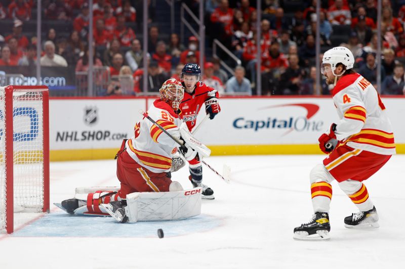 Oct 16, 2023; Washington, District of Columbia, USA; Calgary Flames goaltender Jacob Markstrom (25) makes a save as Washington Capitals center Matthew Phillips (45) and Flames defenseman Rasmus Andersson (4) look on in the third period at Capital One Arena. Mandatory Credit: Geoff Burke-USA TODAY Sports