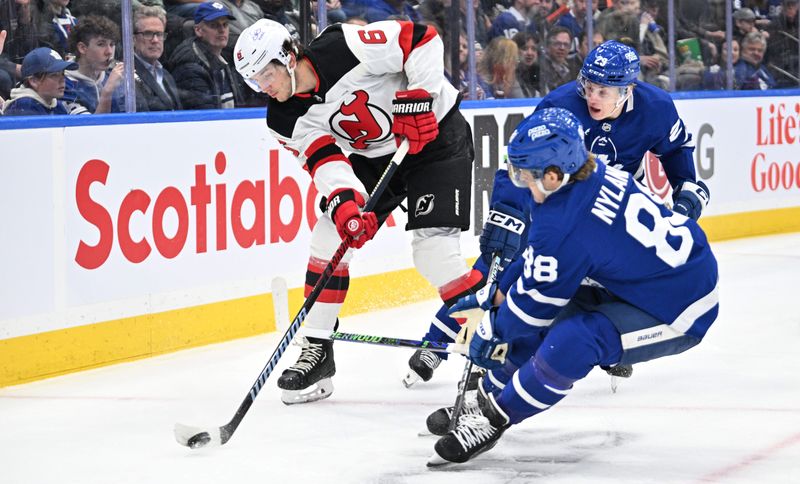 Apr 11, 2024; Toronto, Ontario, CAN; New Jersey Devils defenseman John Marino (6) clears the puck away from Toronto Maple Leafs forwards William Nylander (88) and Matthew Knies (23) in the first period at Scotiabank Arena. Mandatory Credit: Dan Hamilton-USA TODAY Sports