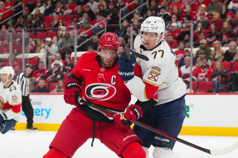 Jan 16, 2026; Raleigh, North Carolina, USA;  Carolina Hurricanes center Jordan Staal (11) and Florida Panthers defenseman Niko Mikkola (77) battle during the first period at Lenovo Center. Mandatory Credit: James Guillory-Imagn Images