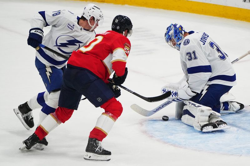 Sep 30, 2024; Sunrise, Florida, USA; Tampa Bay Lightning goaltender Jonas Johansson (31) makes a save as Florida Panthers left wing A.J. Greer (10) closes in during the second period at Amerant Bank Arena. Mandatory Credit: Jim Rassol-Imagn Images