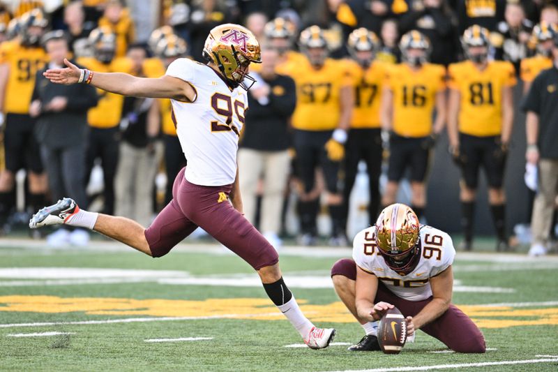 Oct 21, 2023; Iowa City, Iowa, USA; Minnesota Golden Gophers place kicker Dragan Kesich (99) kicks a game winning field goal as punter Mark Crawford (96) holds during the fourth quarter against the Iowa Hawkeyes at Kinnick Stadium. Mandatory Credit: Jeffrey Becker-USA TODAY Sports