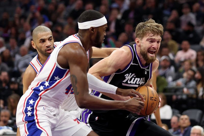 SACRAMENTO, CALIFORNIA - MARCH 25: Domantas Sabonis #10 of the Sacramento Kings is guarded by Paul Reed #44 and Nicolas Batum #40 of the Philadelphia 76ers in the first quarter at Golden 1 Center on March 25, 2024 in Sacramento, California. NOTE TO USER: User expressly acknowledges and agrees that, by downloading and or using this photograph, User is consenting to the terms and conditions of the Getty Images License Agreement.  (Photo by Ezra Shaw/Getty Images)