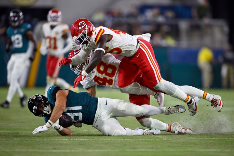 Jacksonville Jaguars tight end Josiah Deguara (81) is stopped by Kansas City Chiefs linebacker Cole Christiansen (48) and safety Tyree Gillespie after catching a pass during the second half of an NFL preseason football game Saturday, Aug. 10, 2024, in Jacksonville, Fla. (AP Photo/Phelan M. Ebenhack)