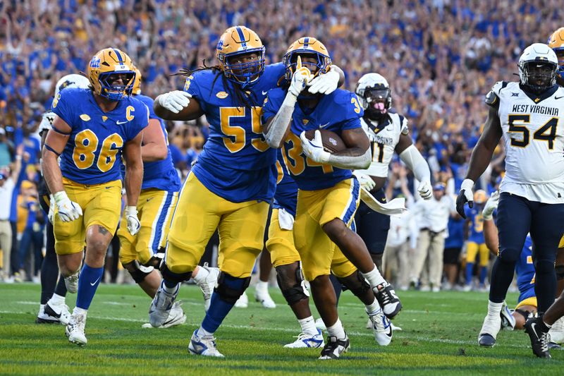 Sep 14, 2024; Pittsburgh, Pennsylvania, USA; Pittsburgh Panthers running back Derrick Davis Jr. (34) celebrates  a touchdown with BJ Williams (55) as West Virginia Mountaineers defensive lineman Fatorma Mulbah (54) looks on during the fourth quarter at Acrisure Stadium. Mandatory Credit: Barry Reeger-Image Images