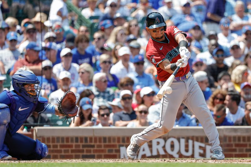 Jul 19, 2024; Chicago, Illinois, USA; Arizona Diamondbacks catcher Gabriel Moreno (14) hits an RBI-single against the Chicago Cubs during the third inning at Wrigley Field. Mandatory Credit: Kamil Krzaczynski-USA TODAY Sports