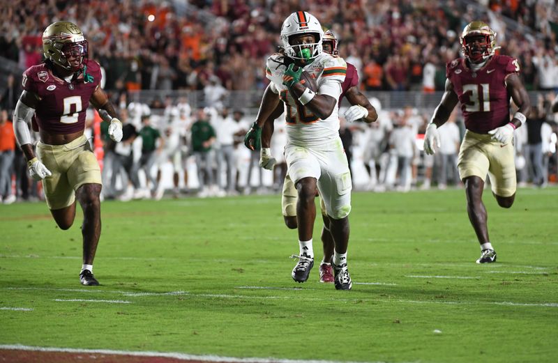 Oct 4, 2025; Tallahassee, Florida, USA; Miami Hurricanes wide receiver Malachi Toney (10) scores a touchdown against Florida State Seminoles defensive back Earl Little Jr., defensive back Jerry Wilson (19) and linebacker Elijah Herring (31) during the second half at Doak S. Campbell Stadium. Mandatory Credit: Robert Myers-Imagn Images