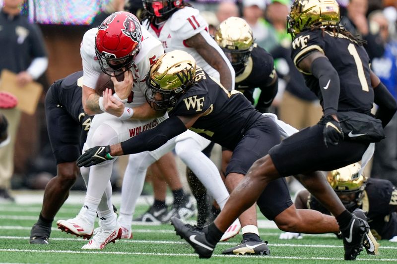 Nov 11, 2023; Winston-Salem, North Carolina, USA; Wake Forest Demon Deacons defensive back Evan Slocum (14) tackles North Carolina State Wolfpack quarterback Brennan Armstrong (5) during the first half at Allegacy Federal Credit Union Stadium. Mandatory Credit: Jim Dedmon-USA TODAY Sports