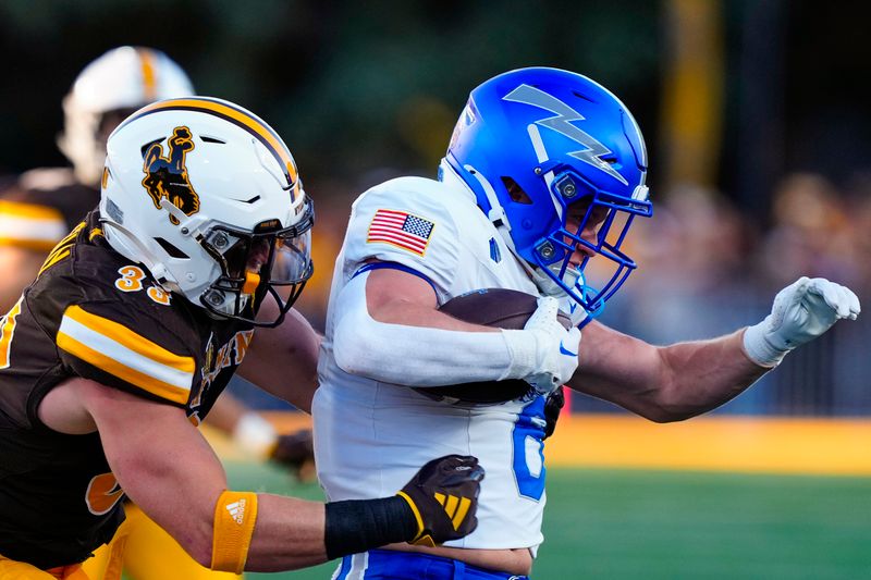 Sep 28, 2024; Laramie, Wyoming, USA; Air Force Falcons running back Kade Frew (8) is tackled by Wyoming Cowboys linebacker Connor Shay (33) during the first quarter at Jonah Field at War Memorial Stadium. Mandatory Credit: Troy Babbitt-Imagn Images