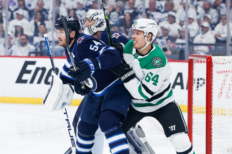 May 7, 2025; Winnipeg, Manitoba, CAN; Winnipeg Jets defenseman Dylan Samberg (54) jostles for position with Dallas Stars forward Mikael Granlund (64) during the first period in game one of the second round of the 2025 Stanley Cup Playoffs at Canada Life Centre. Mandatory Credit: Terrence Lee-Imagn Images