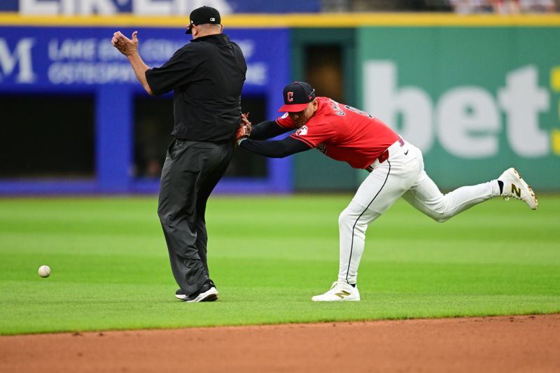 Sep 16, 2024; Cleveland, Ohio, USA; Cleveland Guardians second baseman Andres Gimenez (0) collides with umpire Chad Fairchild while attempting to field a ball hit by Minnesota Twins center fielder Byron Buxton (not pictured) during the third inning at Progressive Field. Mandatory Credit: Ken Blaze-Imagn Images