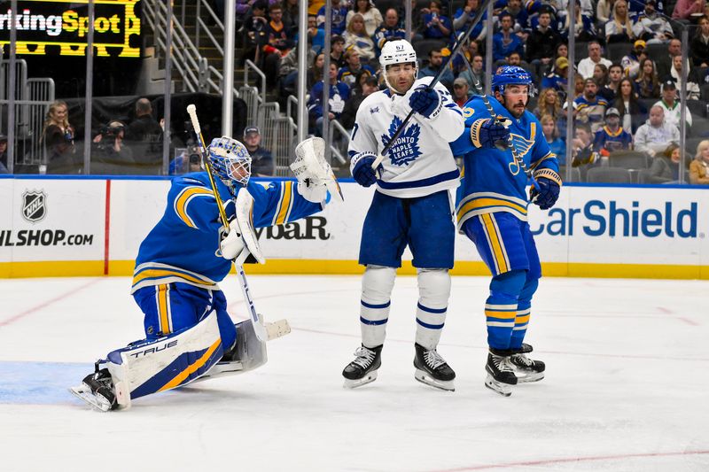 Nov 2, 2024; St. Louis, Missouri, USA;  St. Louis Blues goaltender Jordan Binnington (50) and defenseman Justin Faulk (72) defend the net against Toronto Maple Leafs left wing Max Pacioretty (67) during the third period at Enterprise Center. Mandatory Credit: Jeff Curry-Imagn Images