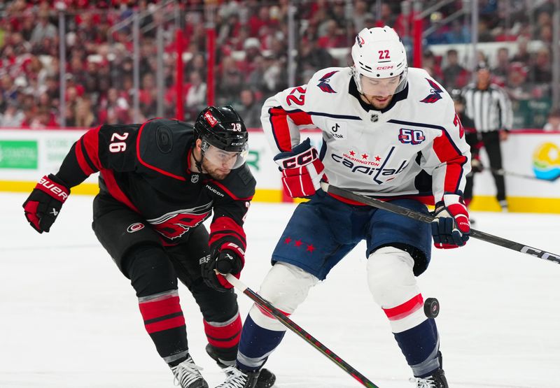 May 10, 2025; Raleigh, North Carolina, USA; Washington Capitals right wing Brandon Duhaime (22) and Carolina Hurricanes defenseman Sean Walker (26) battle over the puck during the first period in game three of the second round of the 2025 Stanley Cup Playoffs at Lenovo Center. Mandatory Credit: James Guillory-Imagn Images