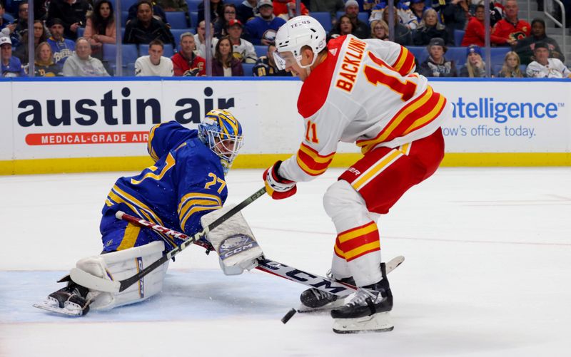 Oct 19, 2023; Buffalo, New York, USA;  Buffalo Sabres goaltender Devon Levi (27) knocks the puck off the stick of Calgary Flames center Mikael Backlund (11) as he skates in on a breakaway during the third period at KeyBank Center. Mandatory Credit: Timothy T. Ludwig-USA TODAY Sports