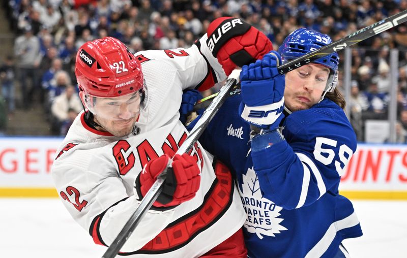 Dec 30, 2023; Toronto, Ontario, CAN; Carolina Hurricanes defenseman Brett Pesce (22) battles for position with Toronto Maple Leafs forward Tyler Bertuzzi (59) in the first period at Scotiabank Arena. Mandatory Credit: Dan Hamilton-USA TODAY Sports