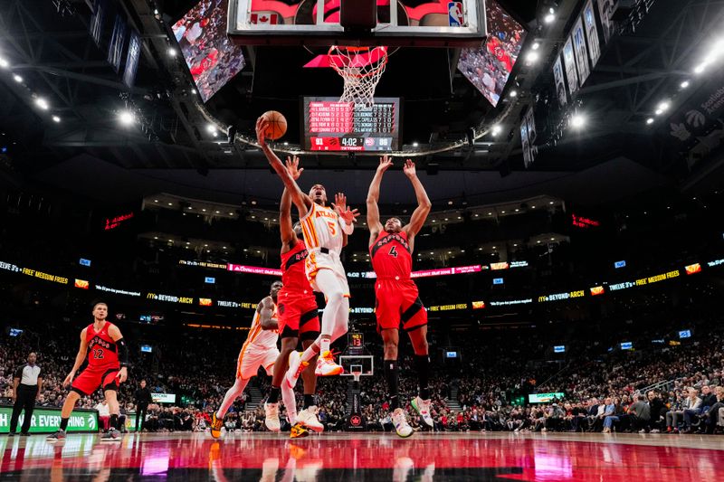 TORONTO, ON - DECEMBER 13: Dejounte Murray #5 of the Atlanta Hawks goes to the basket against Scottie Barnes #4 of the Toronto Raptors during second half NBA action at Scotiabank Arena on December 13, 2023 in Toronto, Ontario, Canada. NOTE TO USER: User expressly acknowledges and agrees that, by downloading and/or using this Photograph, user is consenting to the terms and conditions of the Getty Images License Agreement. (Photo by Andrew Lahodynskyj/Getty Images)