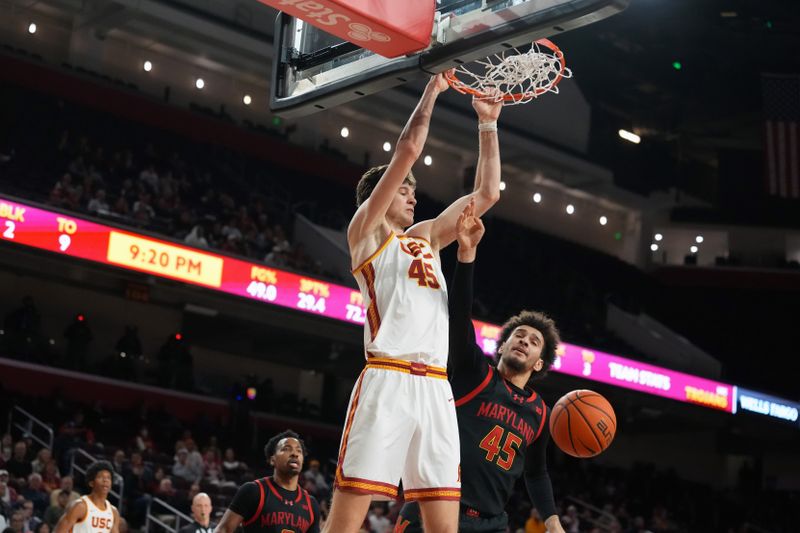 Jan 13, 2026; Los Angeles, California, USA; Southern California Trojans center Gabe Dynes (left) dunks the ball against Maryland Terrapins center Collin Metcalf in the second half at Galen Center. Mandatory Credit: Kirby Lee-Imagn Images