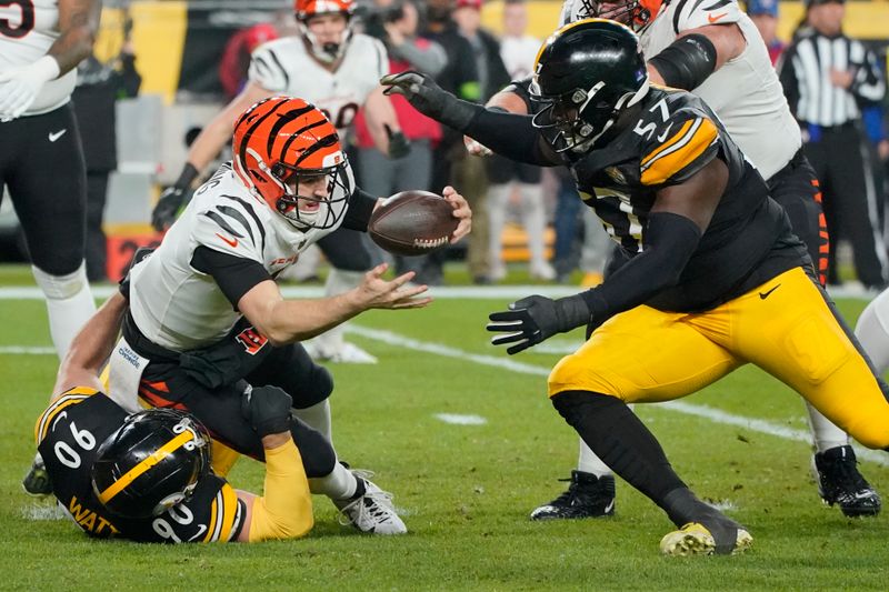 Cincinnati Bengals quarterback Jake Browning (6) is sacked by Pittsburgh Steelers linebacker T.J. Watt (90) as Pittsburgh Steelers defensive tackle Montravius Adams (57) moves in during the first half of an NFL football game Saturday, Dec. 23, 2023, in Pittsburgh. (AP Photo/Gene J. Puskar)