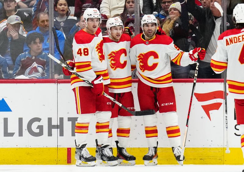 Dec 11, 2023; Denver, Colorado, USA; Calgary Flames defenseman Chris Tanev (88) celebrates his goal with defenseman Dennis Gilbert (48) and center Nazem Kadri (91) in the second period against the Colorado Avalanche at Ball Arena. Mandatory Credit: Ron Chenoy-USA TODAY Sports