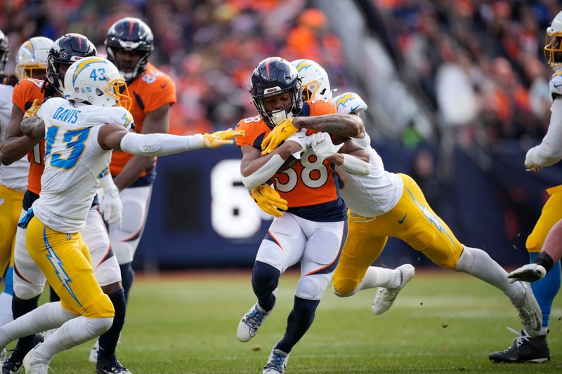 Denver Broncos running back Jaleel McLaughlin (38) is stopped by Los Angeles Chargers cornerback Michael Davis (43) and Los Angeles Chargers safety Derwin James Jr. (3) in the first half of an NFL football game in Empower Field at Mile High Sunday, Dec. 31, 2023, in Denver. (AP Photo/David Zalubowski)