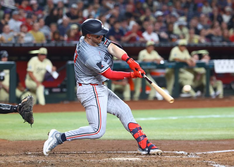 Jun 25, 2024; Phoenix, Arizona, USA; Minnesota Twins catcher Ryan Jeffers hits a three run home run in the seventh inning against the Arizona Diamondbacks at Chase Field. Mandatory Credit: Mark J. Rebilas-USA TODAY Sports