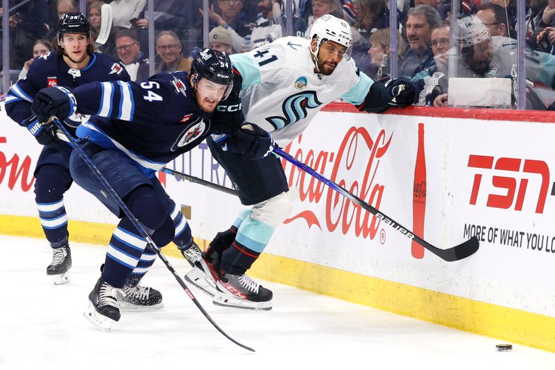 Mar 5, 2024; Winnipeg, Manitoba, CAN; Winnipeg Jets defenseman Dylan Samberg (54) and Seattle Kraken left wing Pierre-Edouard Bellemare (41) chase after the puck in the first period at Canada Life Centre. Mandatory Credit: James Carey Lauder-USA TODAY Sports