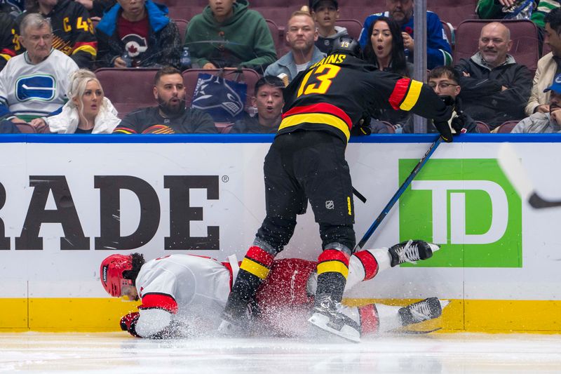 Oct 28, 2024; Vancouver, British Columbia, CAN; Vancouver Canucks forward Arshdeep Bains (13) checks Carolina Hurricanes defenseman Jalen Chatfield (5) during the third period at Rogers Arena. Mandatory Credit: Bob Frid-Imagn Images