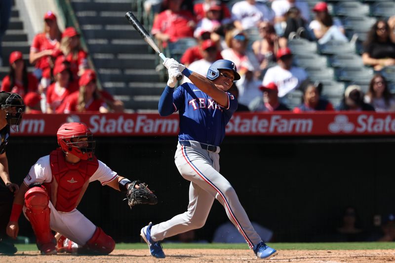 Sep 29, 2024; Anaheim, California, USA;  Texas Rangers designated hitter Dustin Harris (38) hits an RBI double, his first MLB hit, during the seventh inning against the Los Angeles Angels at Angel Stadium. Mandatory Credit: Kiyoshi Mio-Imagn Images